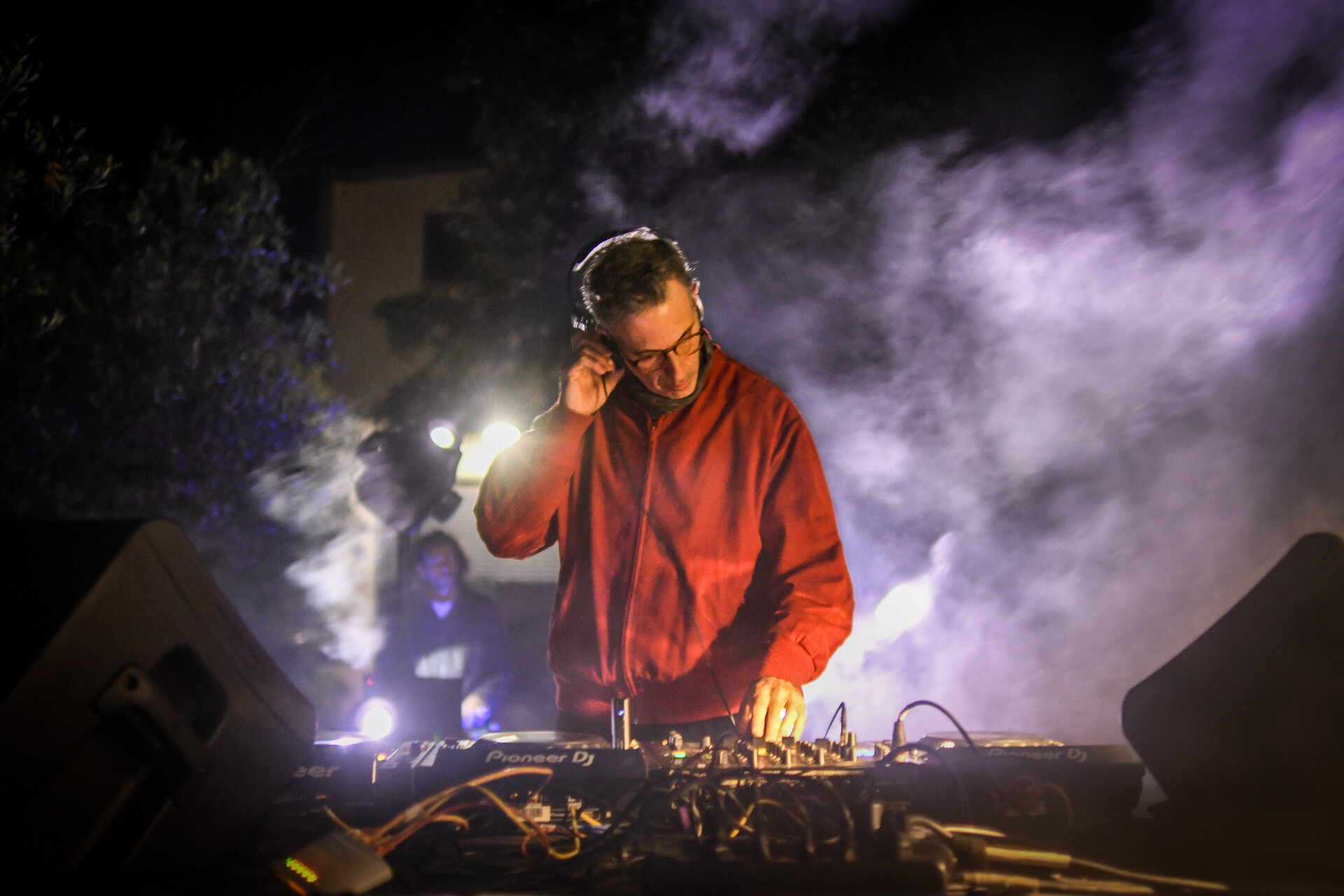 DJ mixing behind the decks under colored stage lighting in San Antonio